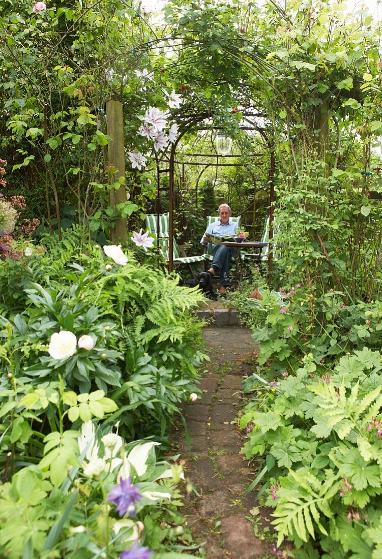 Steg führt durch üppigen Garten zu einem Sitzplatz