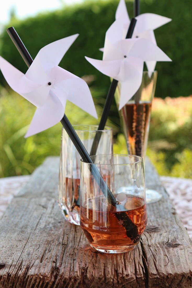 Hand-made windmills on drinking straws decorating glasses for garden party