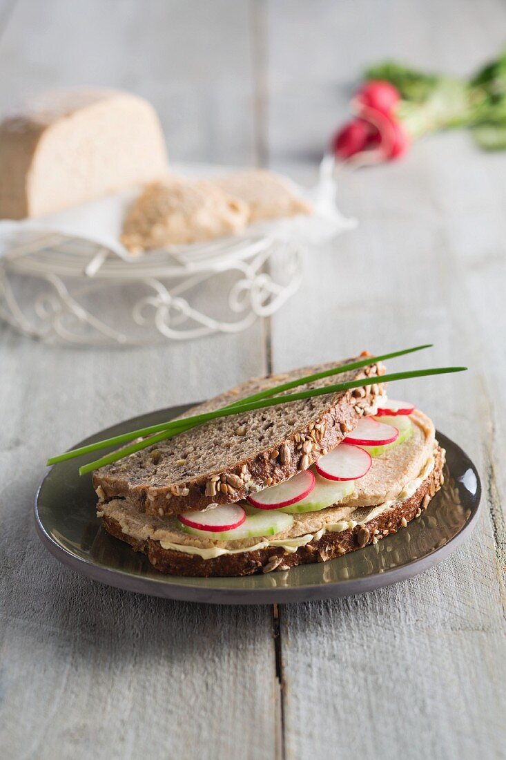 A wholemeal sandwich with ripe cashew nut cheese and radishes (vegan)