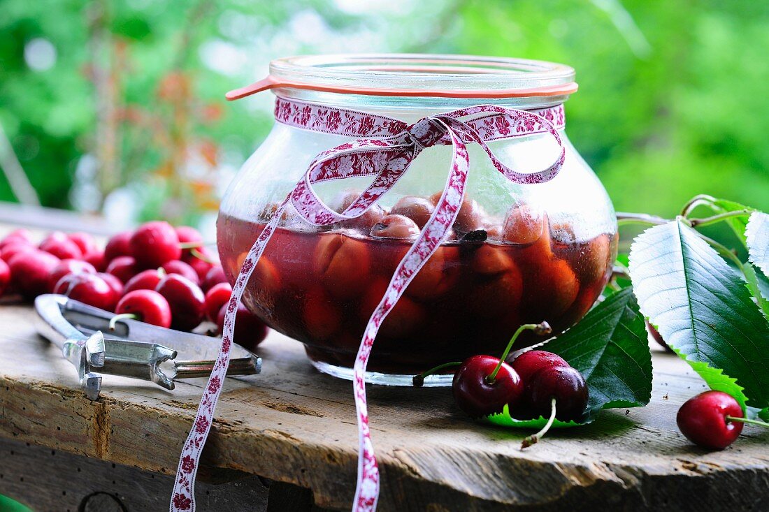 Cherry compote in a jar and fresh cherries on a rustic wooden table
