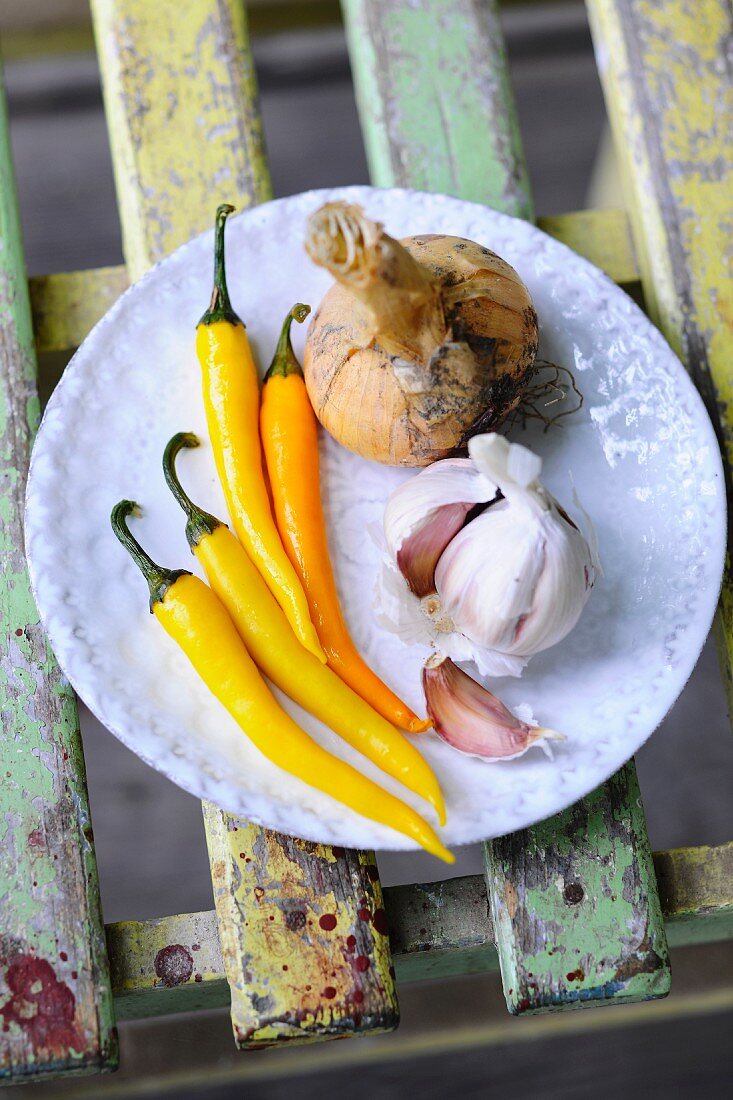 Gelbe Chilischoten, Knoblauch und Zwiebel auf Teller