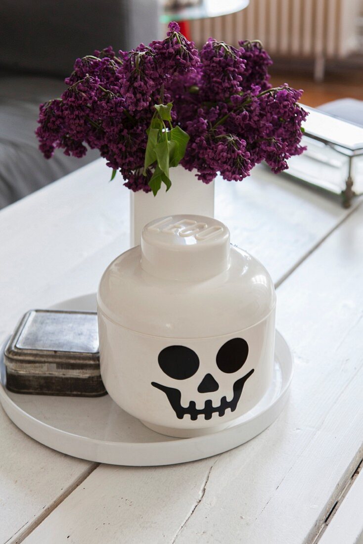 Lego-style skull pot in front of vase of lilac