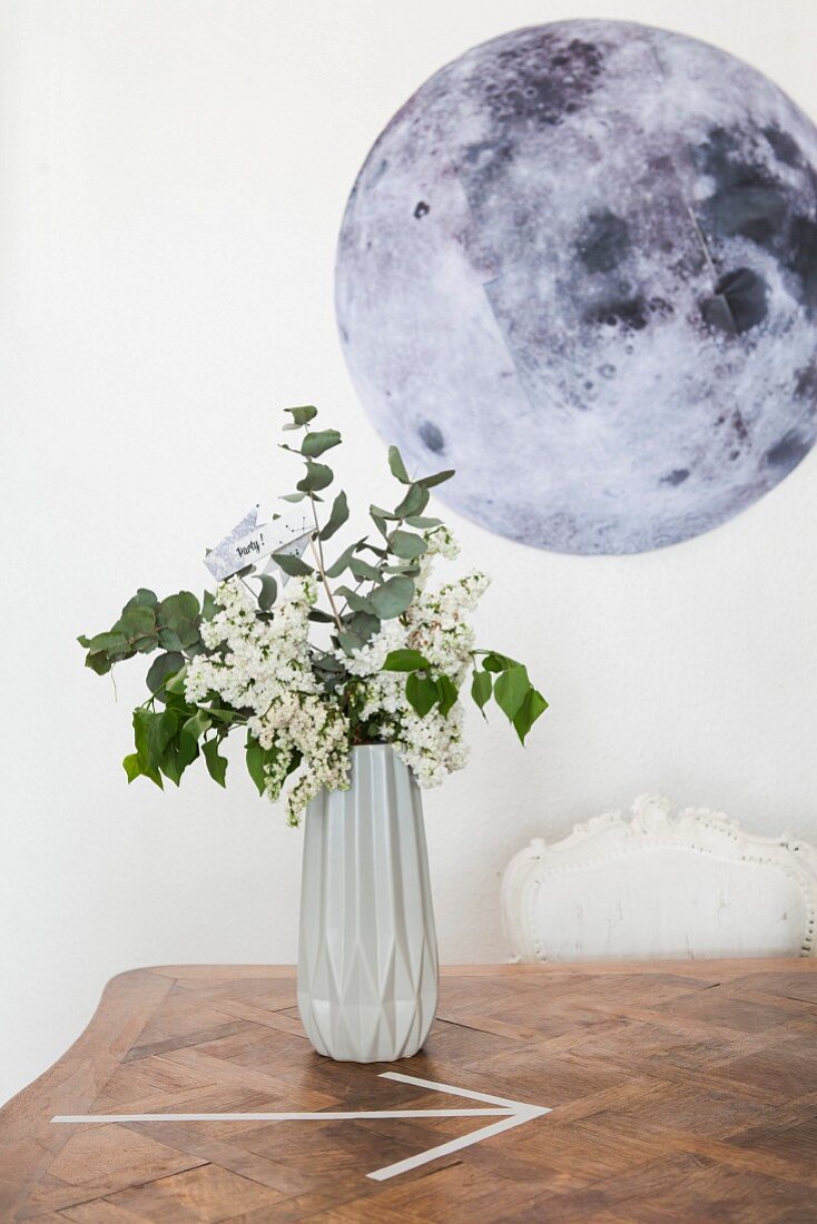 Vase mit geometrischer Form, dahinter ein Mond-Bild