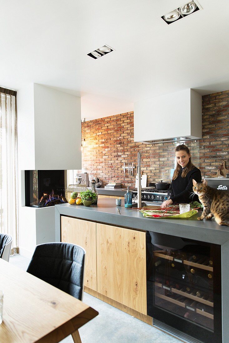 Woman and cat in modern kitchen with brick wall