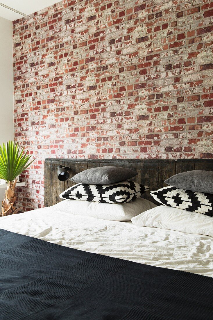 Bed with rustic headboard against brick wall in bedroom