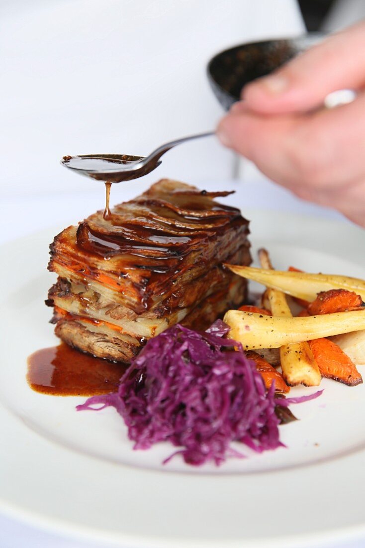Layered lamb shoulder with potatoes served with red cabbage and root vegetables
