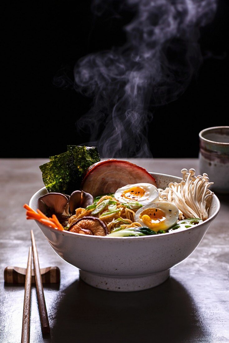 A steaming bowl of ramen noodle soup with mushrooms, prawns, pork belly and egg (Japan)