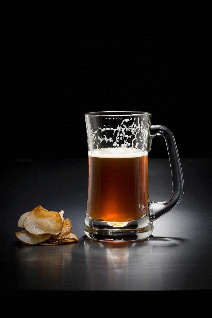 A glass of dark beer and crisps