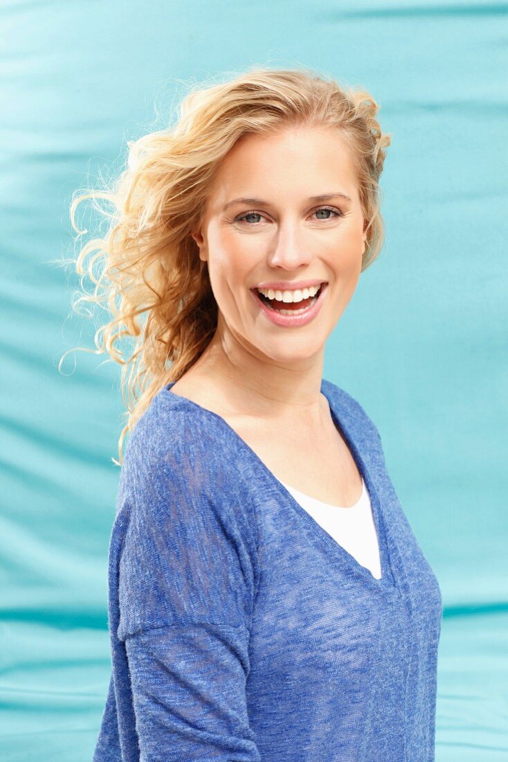 A young blonde woman wearing a long-sleeved, mottled, blue top