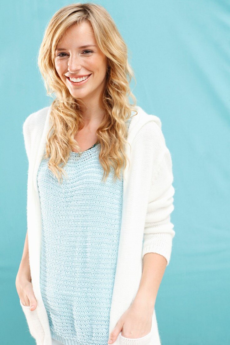 A young blonde woman wearing a knitted top and a jacket