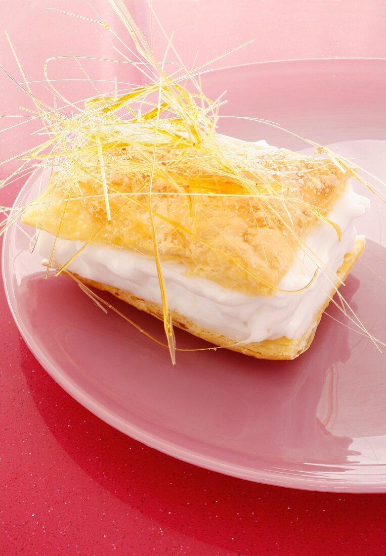 A puff pastry slice with cream and caramel threads