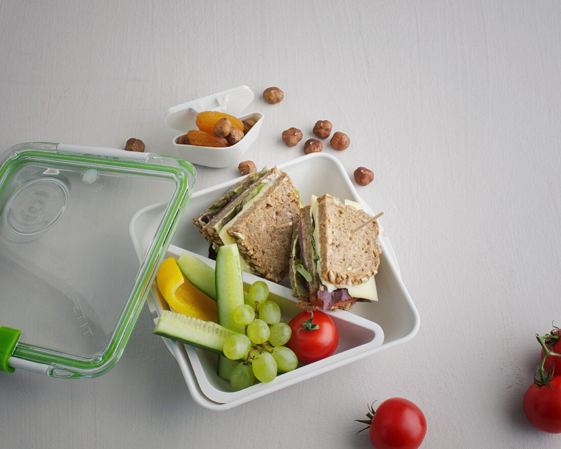 A sandwich, fruit and vegetables in a lunch box