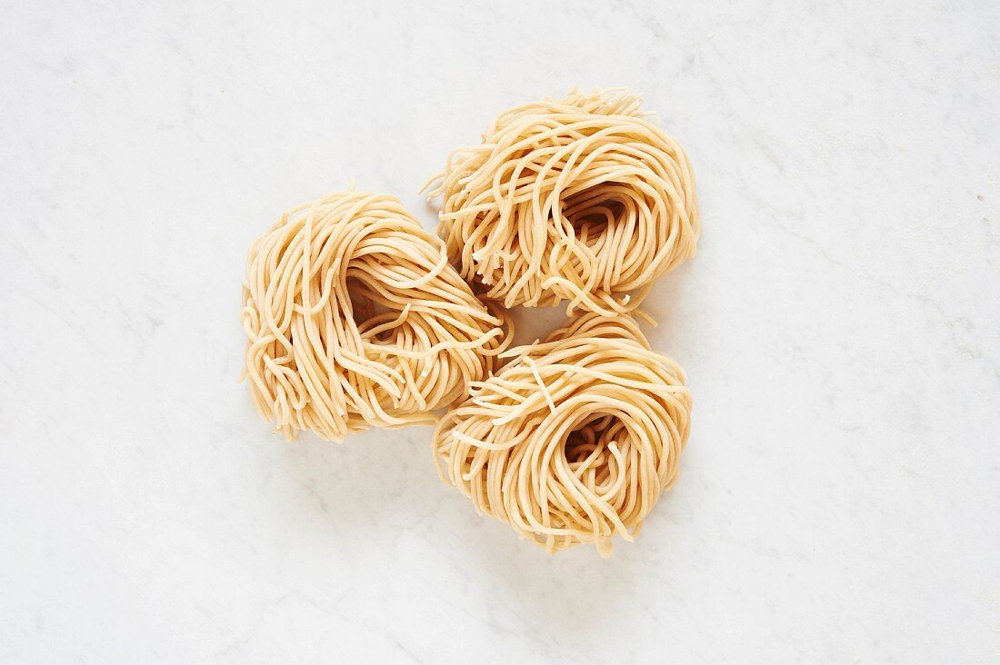 Fresh Pasta: three pasta nests on a white surface (seen from above)