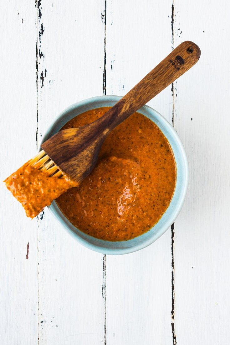 Harissa sauce in a blue bowl with a brush