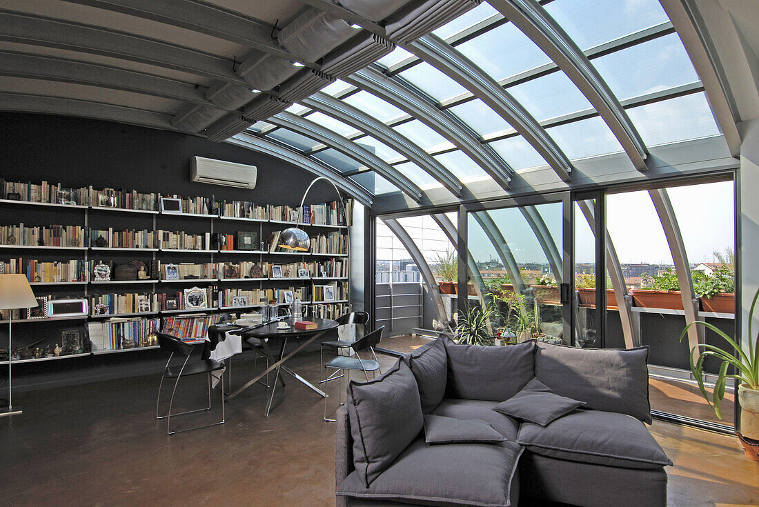 Bücherwand, Essbereich und Lounge in offenem Wohnraum mit Metall- und Glaselementen