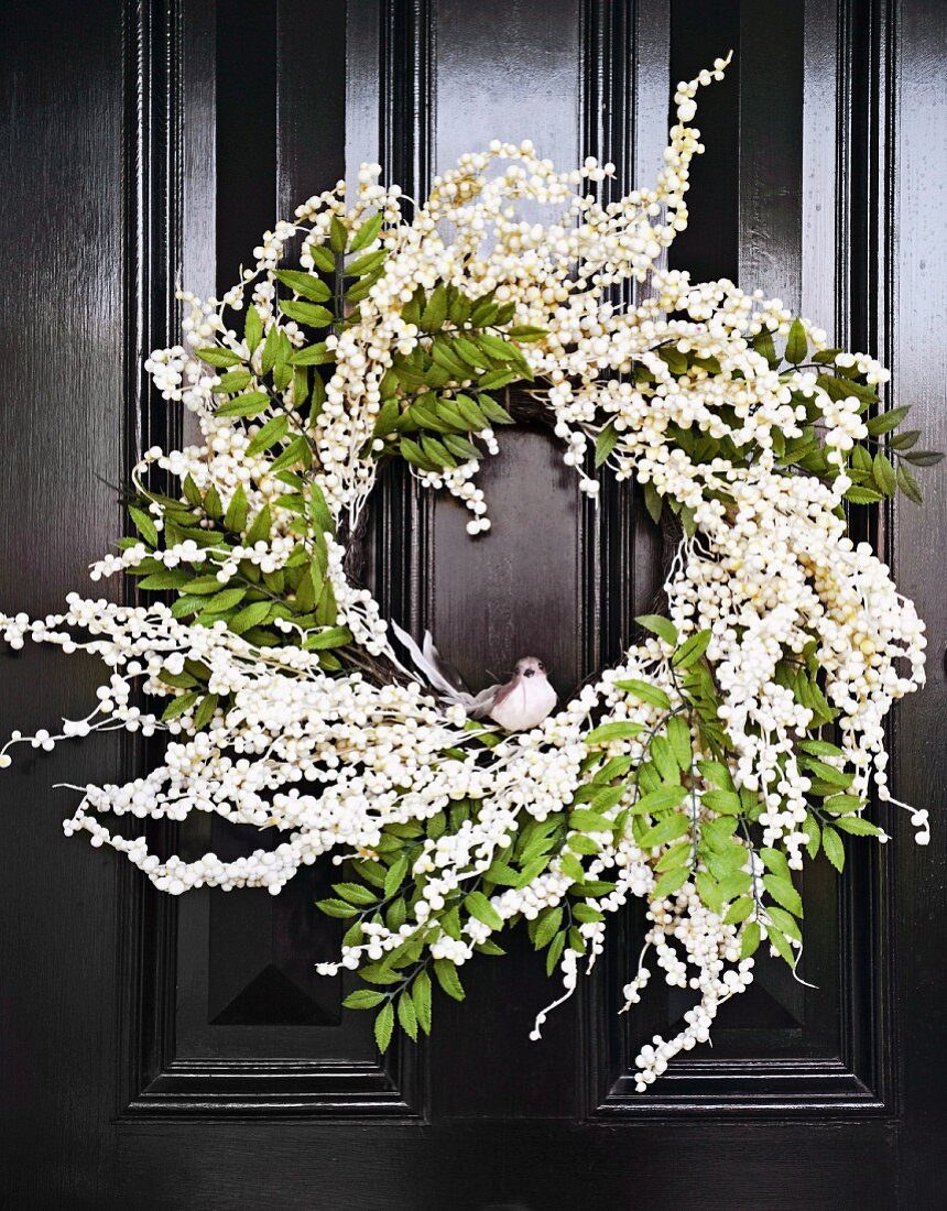 Door wreath of white flowers and decorative bird on black cassette door