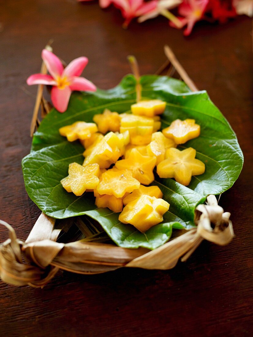 Star fruits cut out in the shape of flowers on a tropical leaf