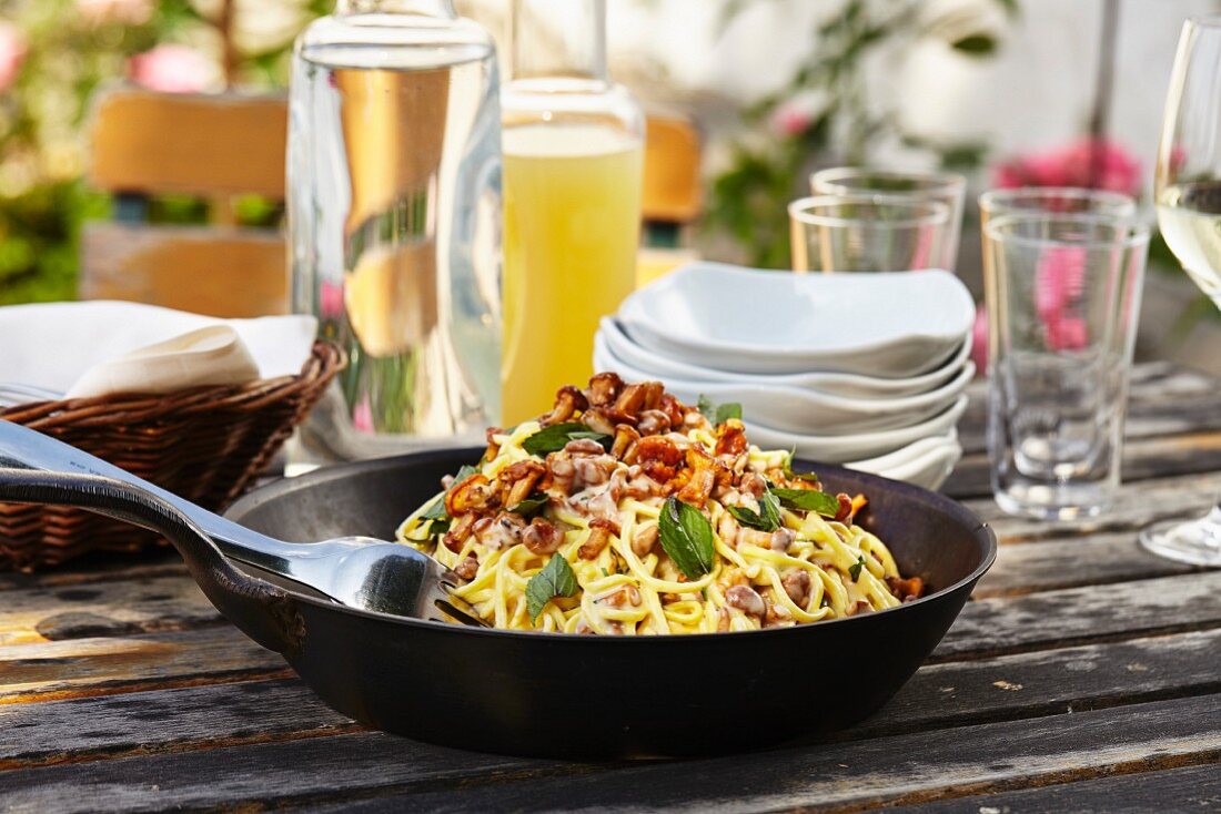 Spaghetti with chanterelle mushrooms in a pan on a garden table