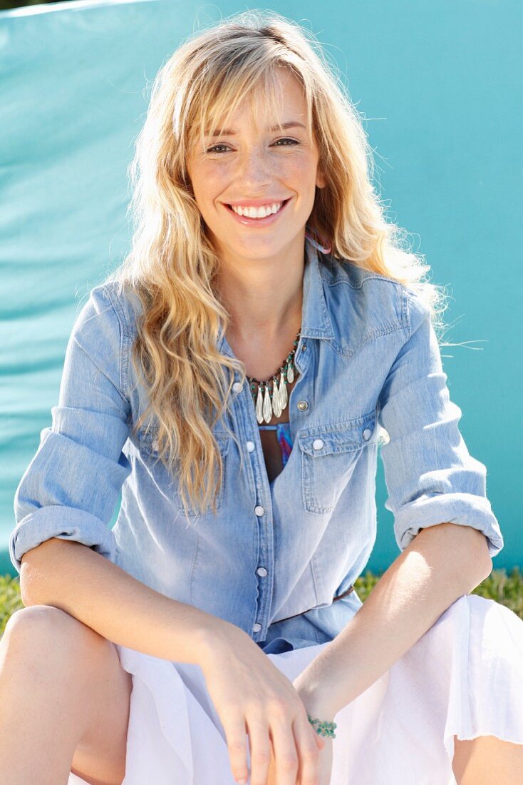 A young blonde woman wearing a denim shirt and a wide skirt