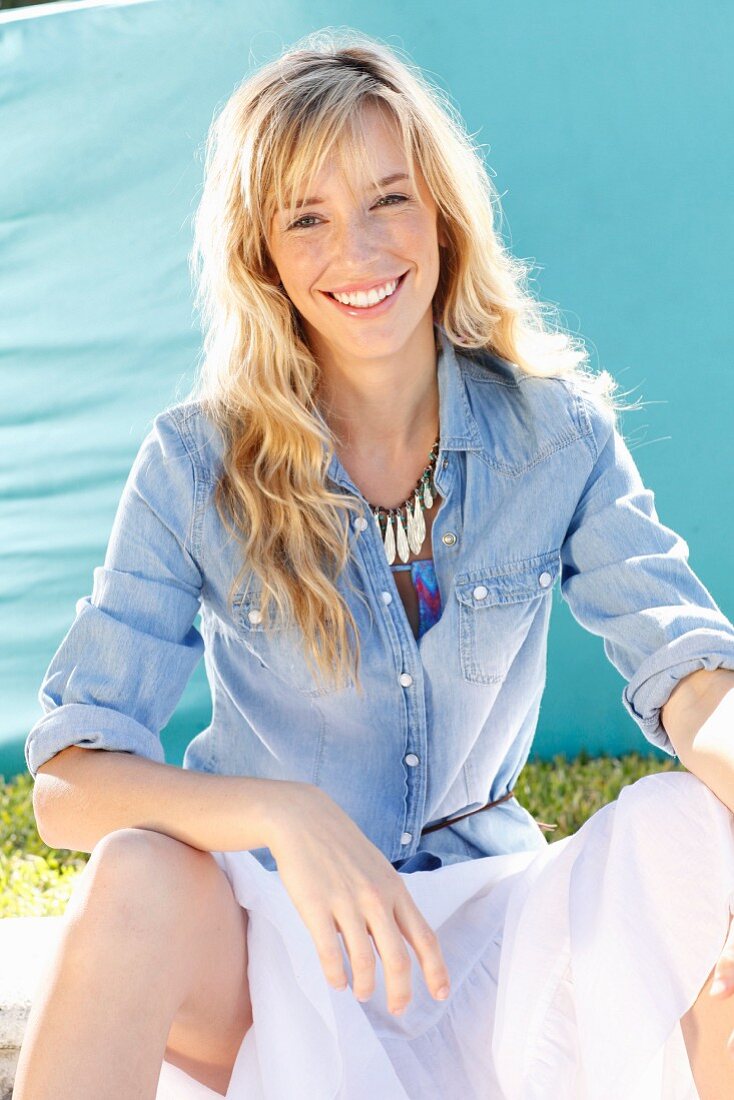 A young blonde woman wearing a denim shirt and a wide skirt