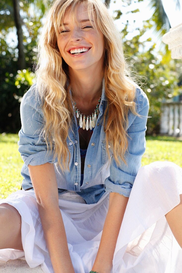 A young blonde woman wearing a denim shirt and a wide skirt