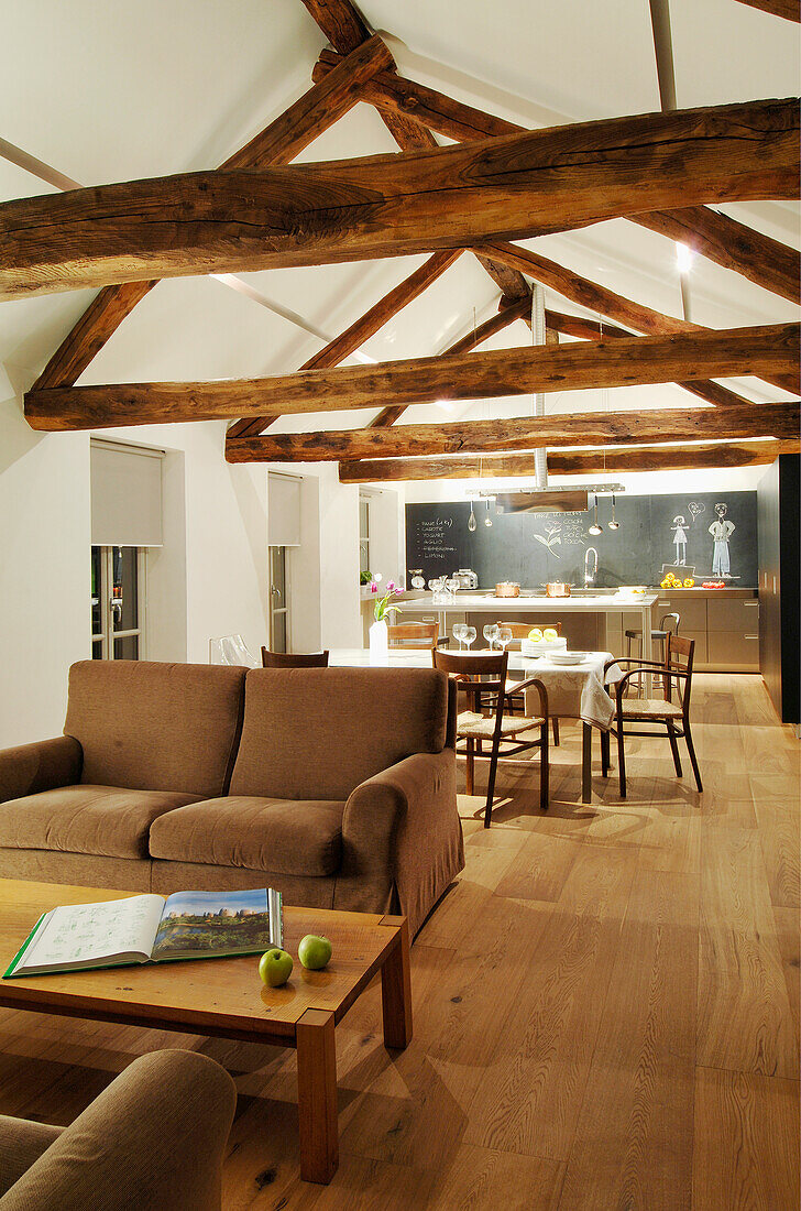 Brown couch and coffee table in an open living room with wooden beams