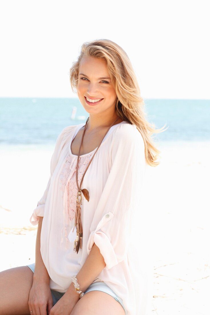 A young woman wearing shorts and a tunic on a beach