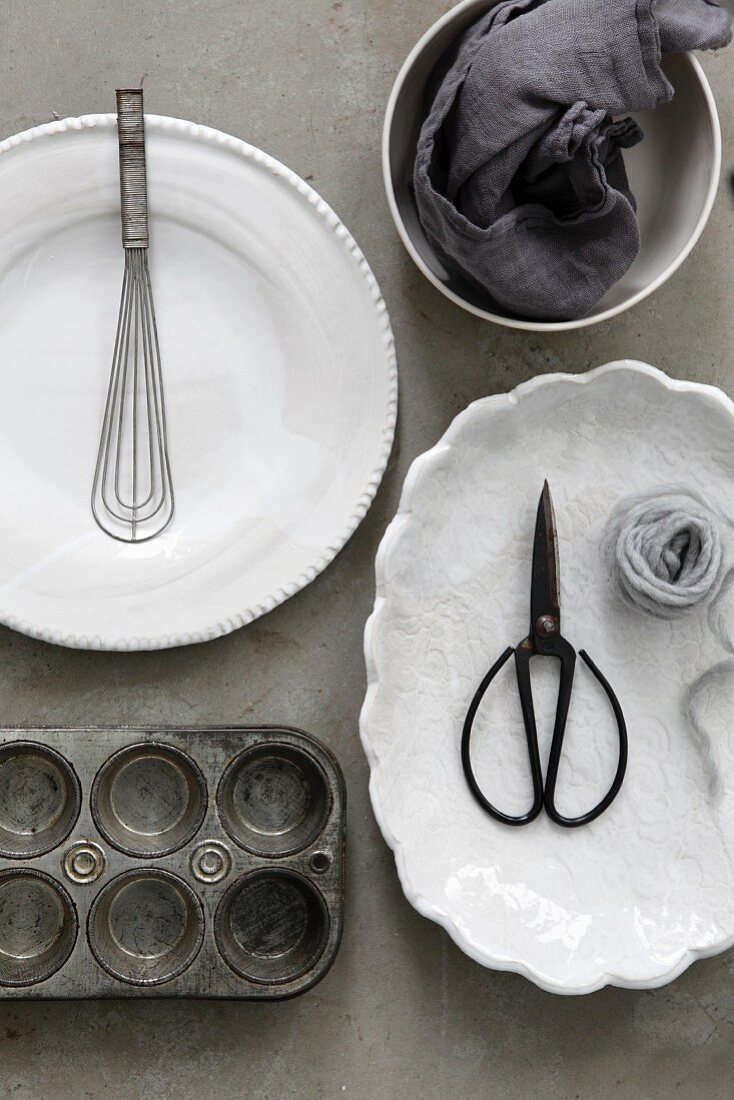 Baking utensils and white crockery on a grey surface