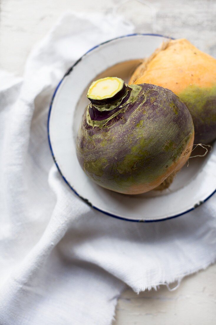 Organic turnips on an enamel plate on a linen cloth