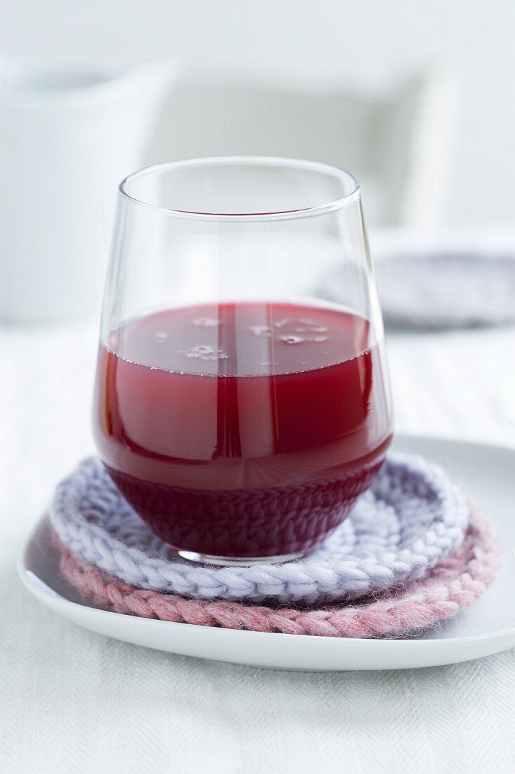 A glass of freshly pressed pomegranate juice on homemade, crocheted coasters