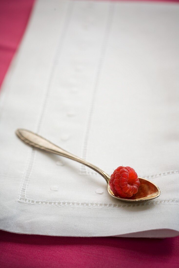 A raspberry on a silver spoon