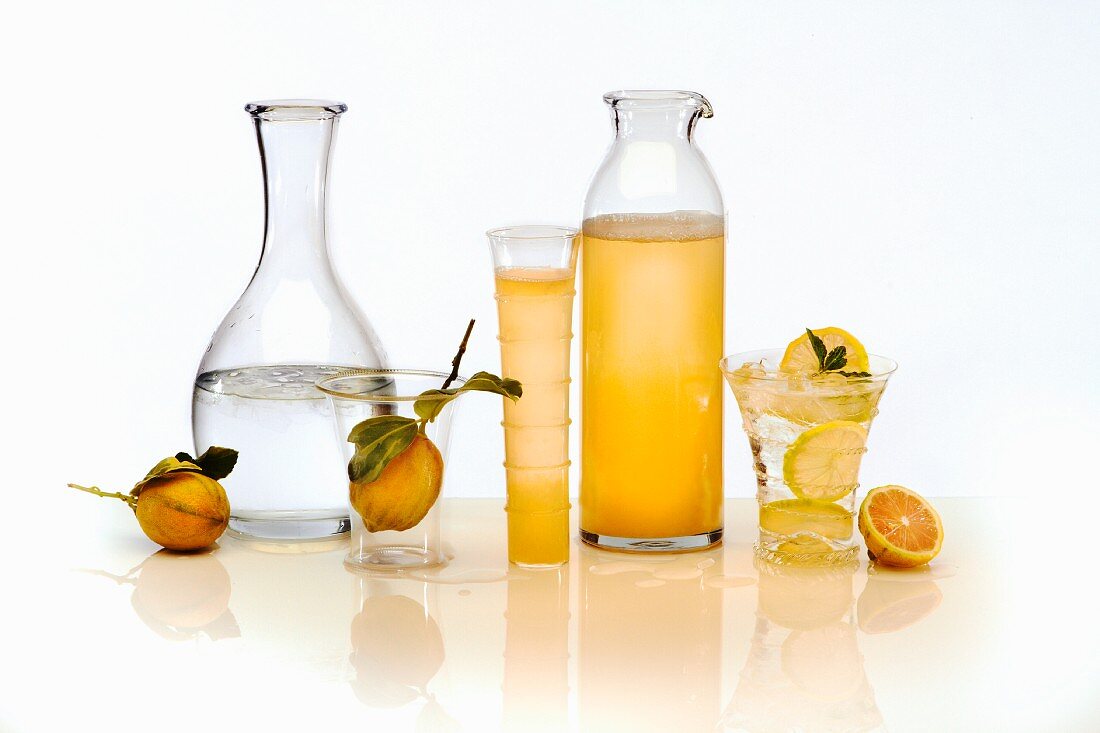 Zitronensaft und Wasser in Gläsern und Karaffen