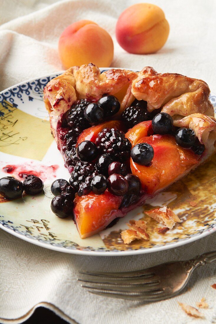 A slice of fruit tart with berries and apricots