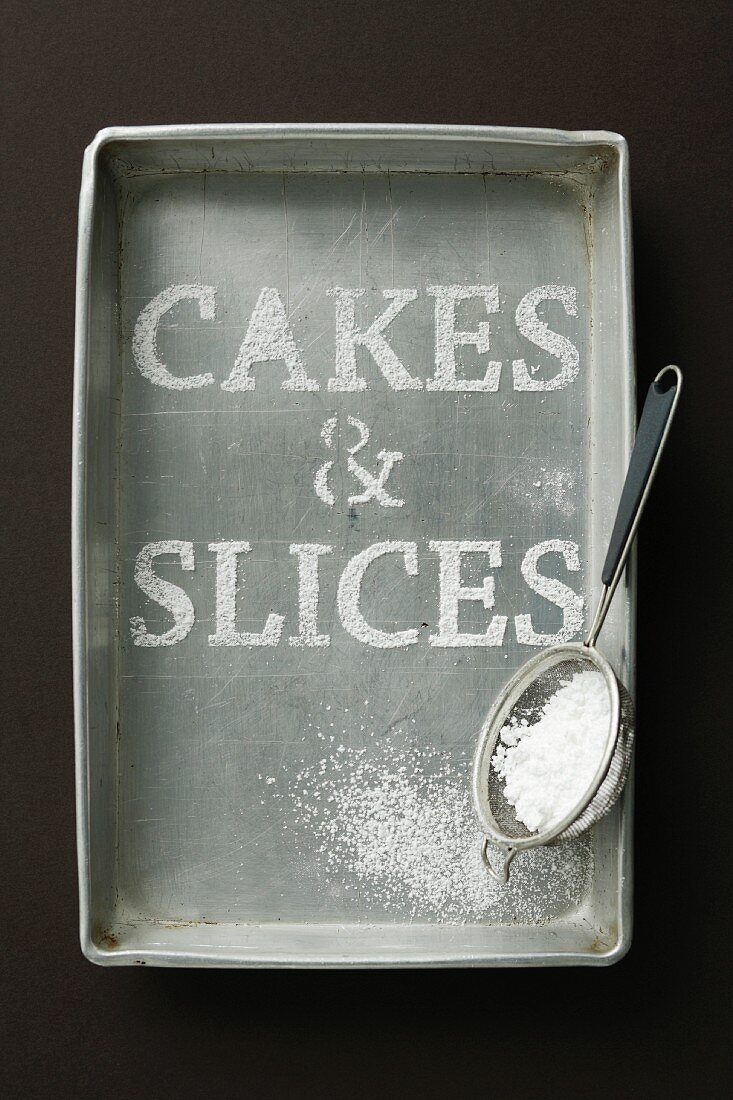 Schriftzug 'Cakes & Slices' aus Puderzucker in Metallbackform