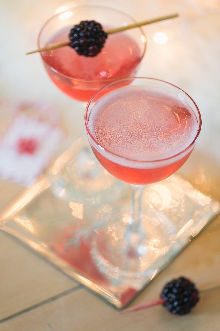Festive champagne cocktails with liqueur and a blackberry garnish