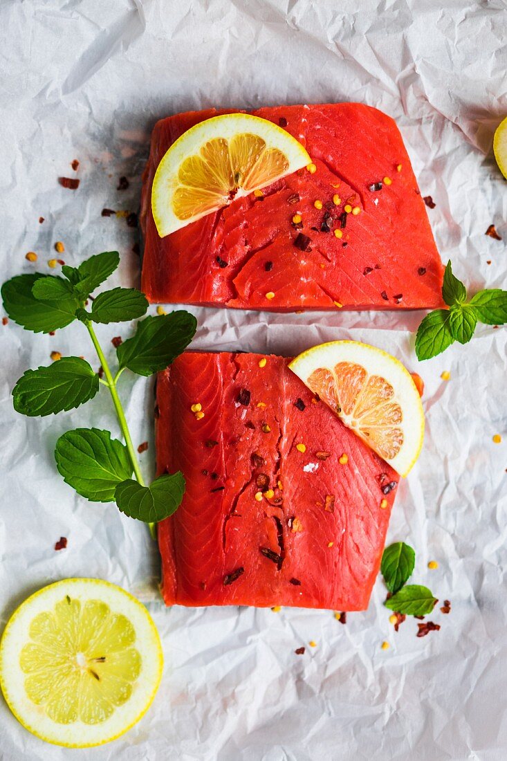 Raw wild salmon with mint, lemon and spices on a piece of white paper