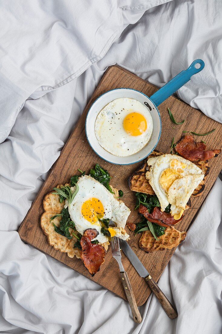 A hearty breakfast with fresh waffles, spinach, bacon and fried eggs