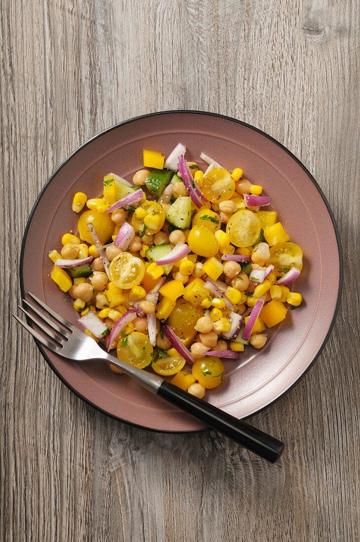 Gelber Gemüsesalat mit Tomaten, Mais, Paprika und Kichererbsen