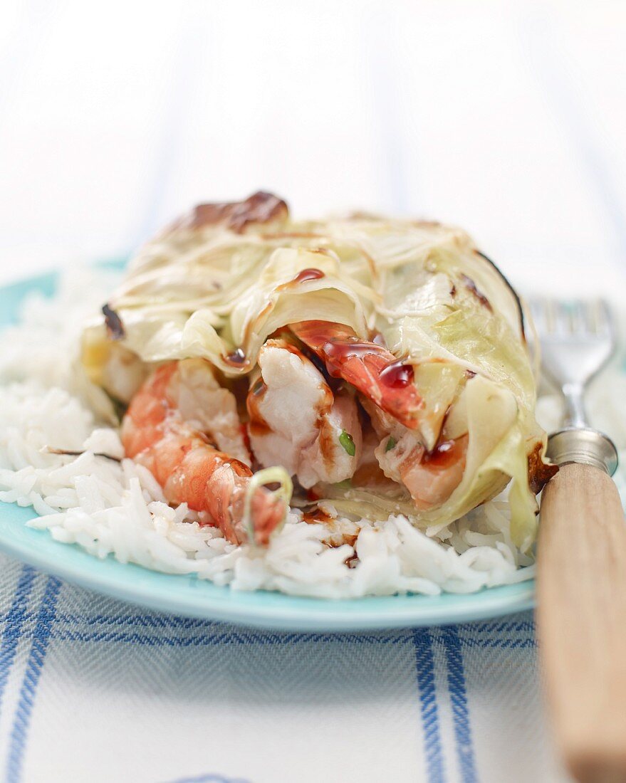 Grilled fish parcel wrapped in cabbage on a bed of rice