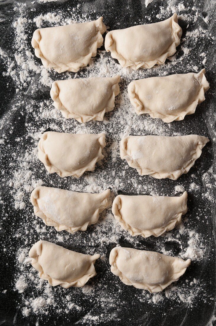 Homemade wareniki (East Polish pierogi) on a floured granite surface