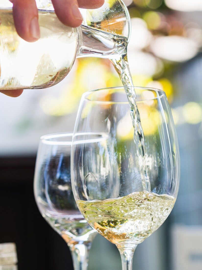 Weißwein aus Südafrika in ein Glas einschenken
