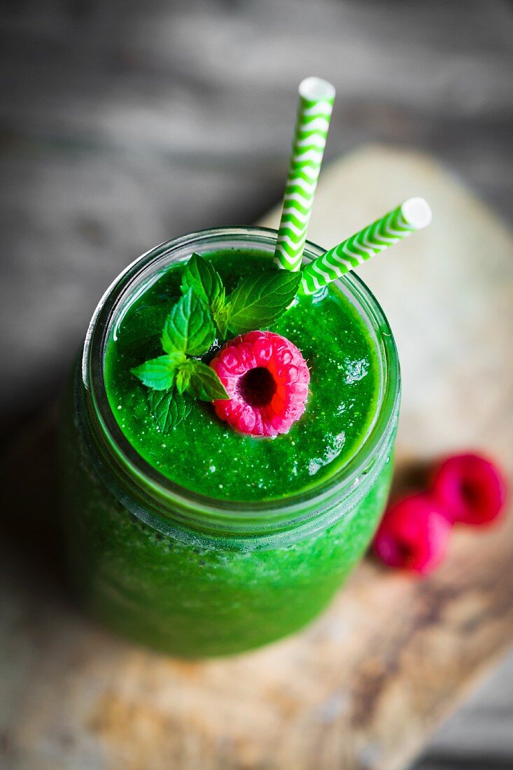 A green smoothie garnished with a raspberry