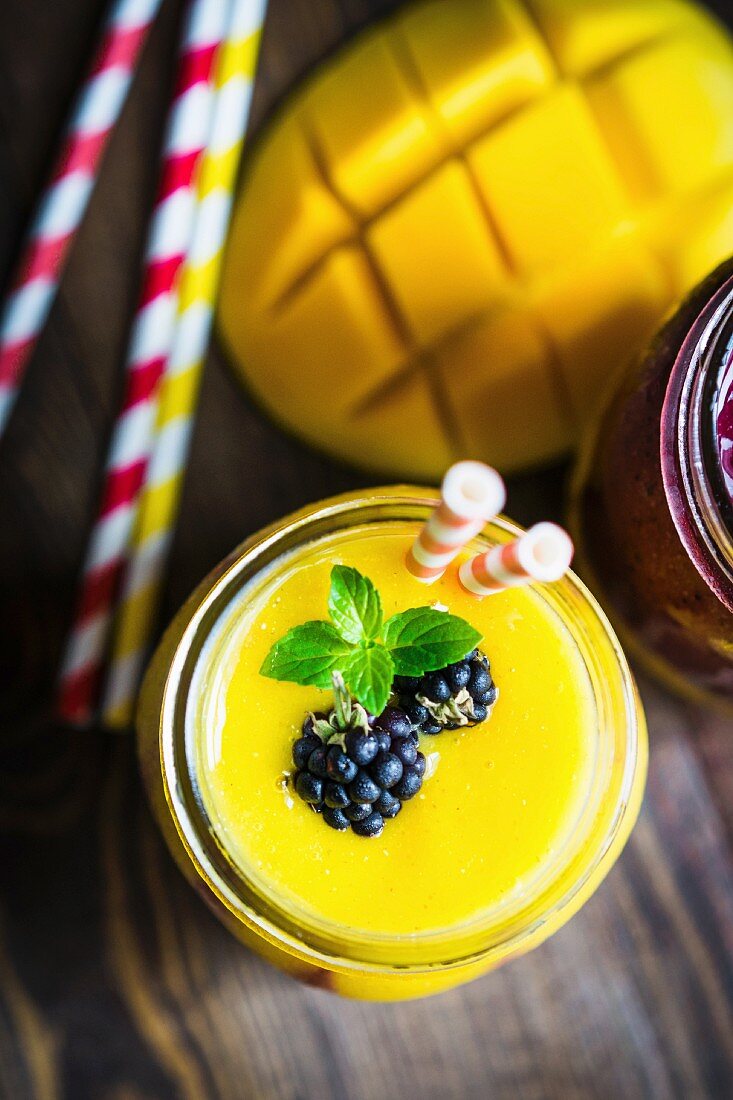 Layered mango and berry smoothie garnished with blackberries