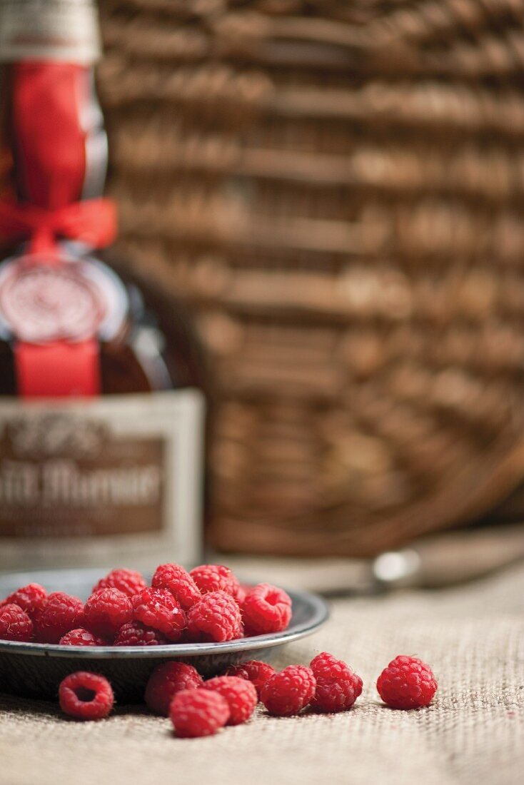 Fresh raspberries with a bottle of liqueur in the background