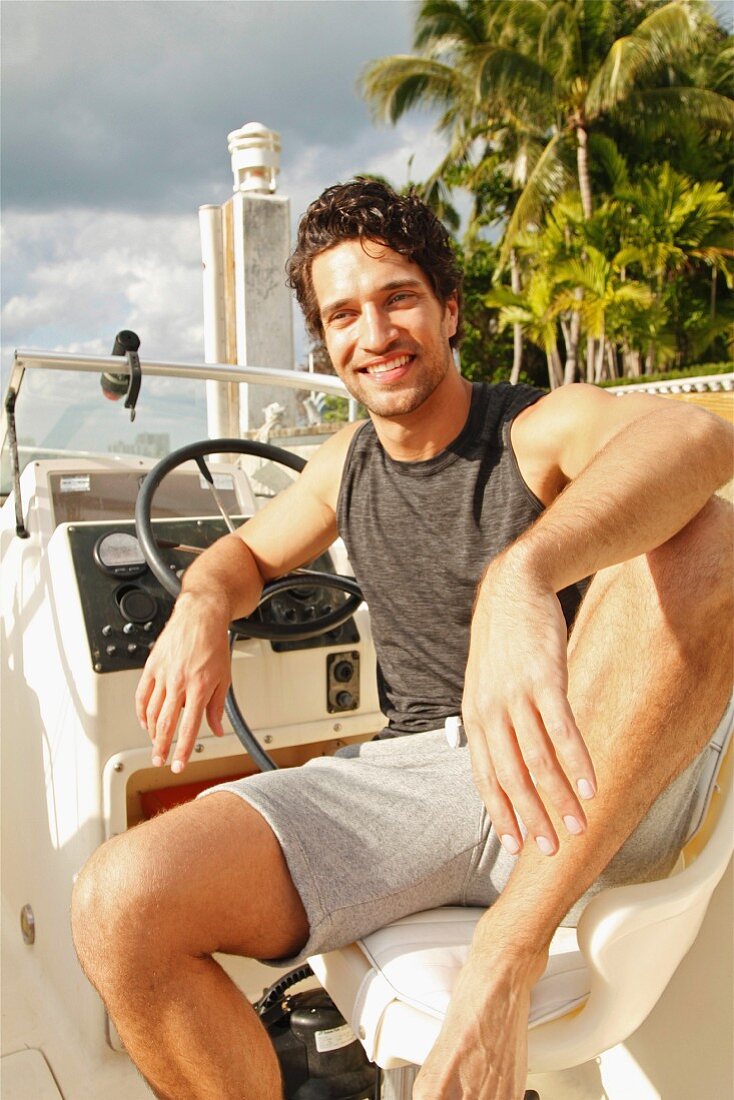 A young man sitting at the wheel of a motor boat