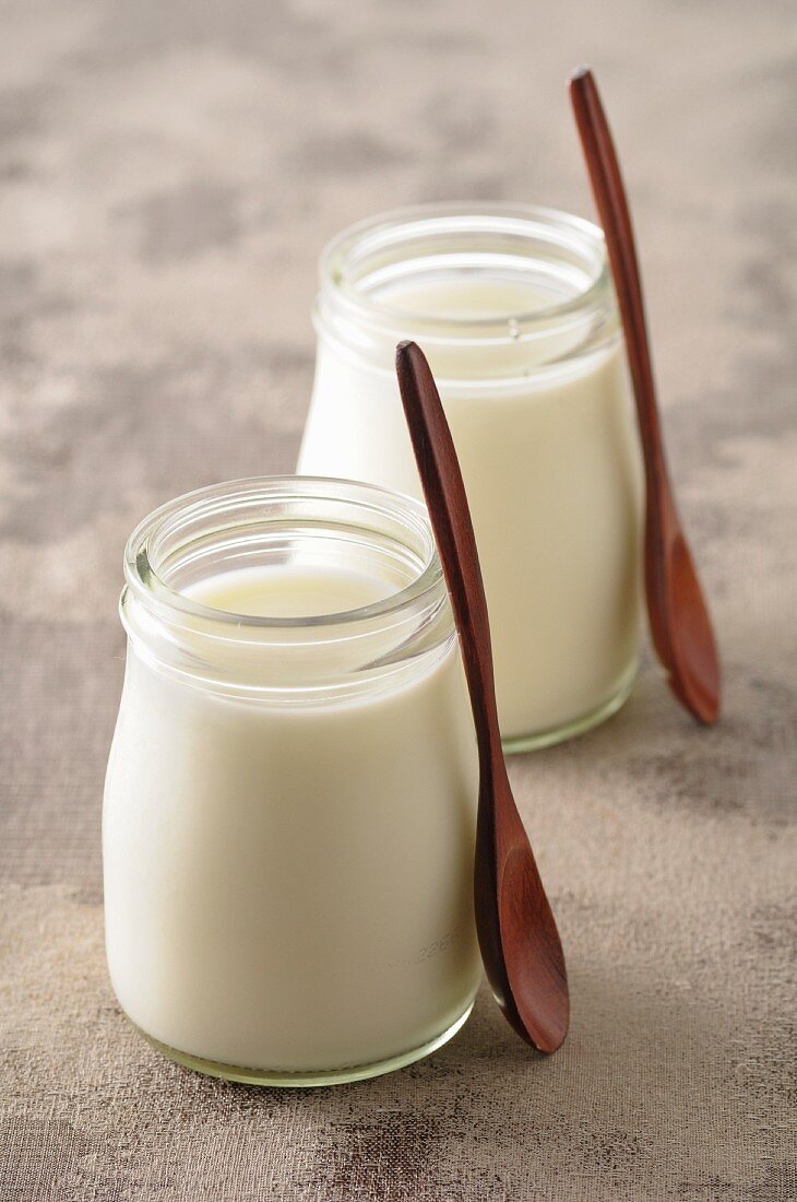 Two glasses of natural yoghurt with wooden spoons