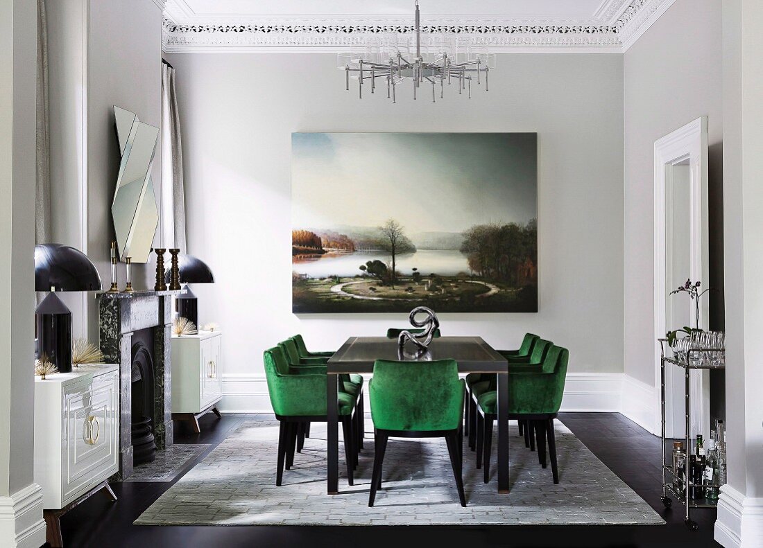 Glamorous dining room with green velvet upholstered chairs and a large landscape painting