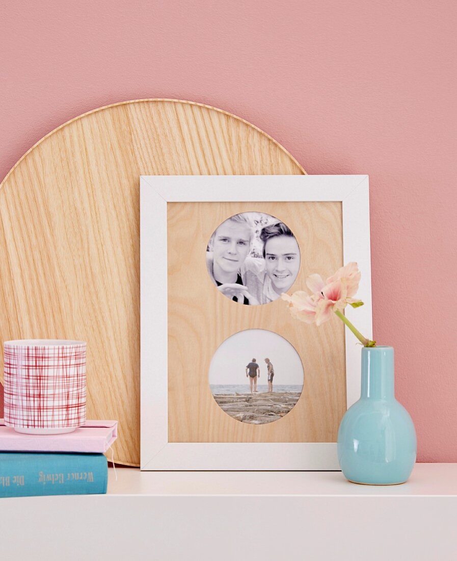 A blue vase next to framed photos with a homemade wooden passepartout