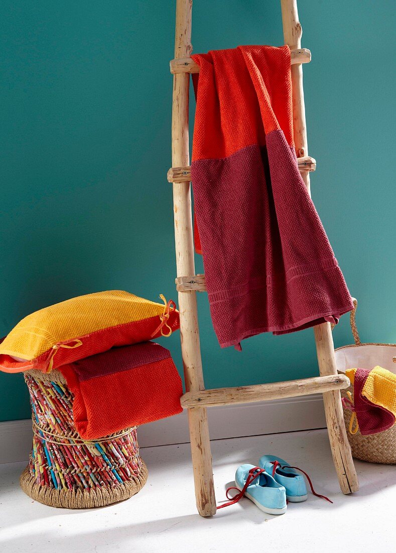 Towel dyed in various shades of red hung over a wooden ladder