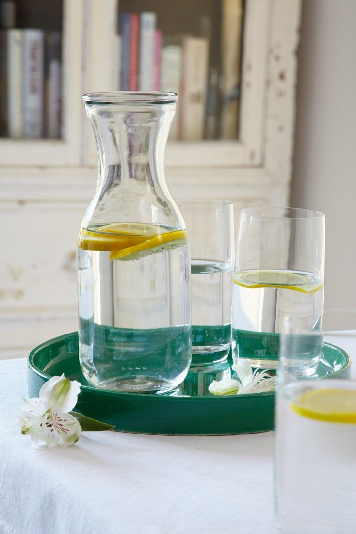 Zitronenwasser in Karaffe und Gläsern auf Tablett